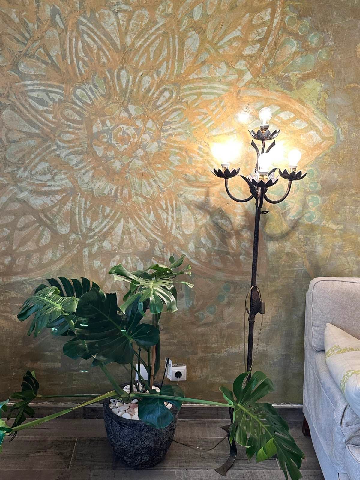 Hand-painted mandala wall with chandelier and monstera plant