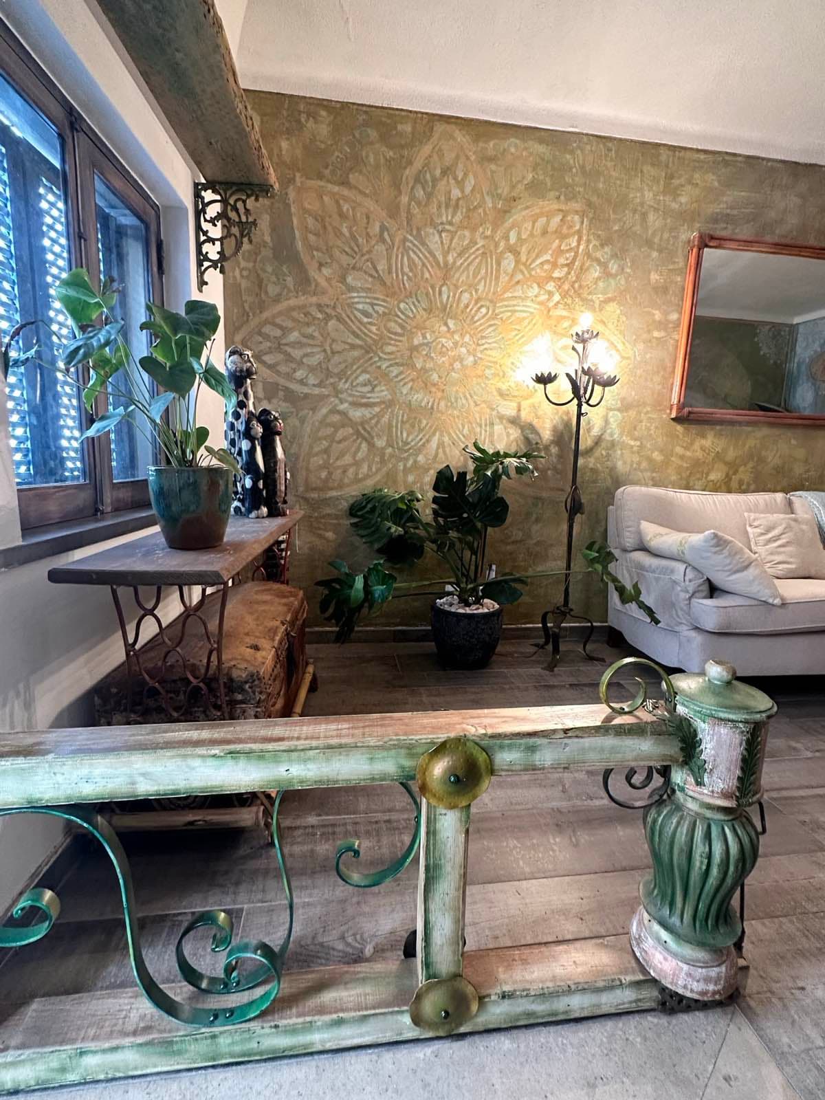Wrought iron staircase with mandala wall and trailing plants
